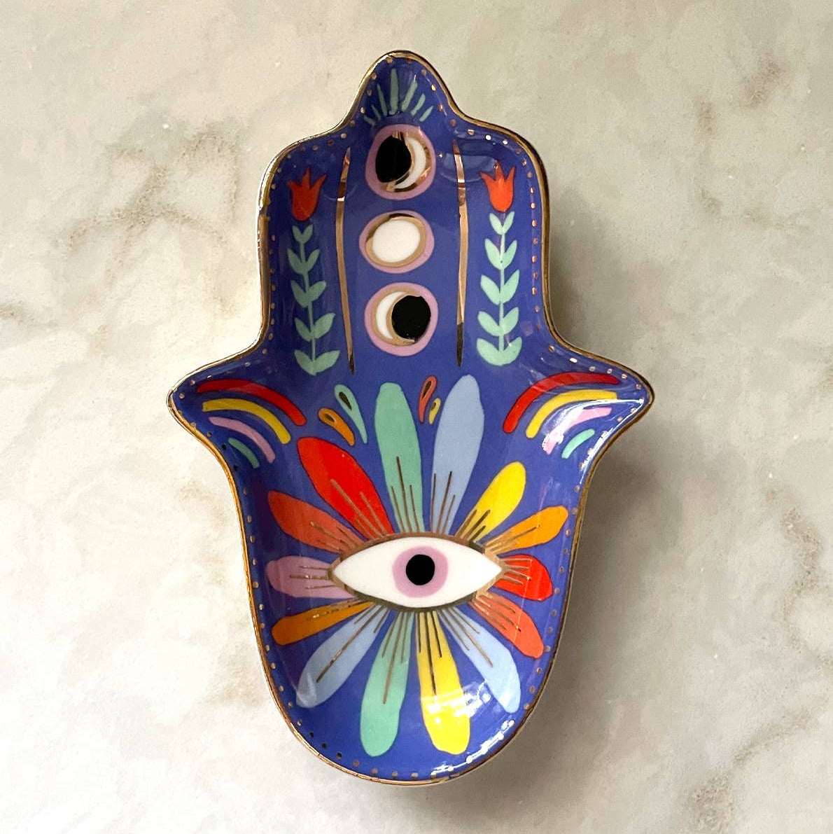 A blue Hamsa hand trinket dish with colorful floral designs